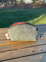 The Seashell Pouch in Black and White Herringbone Harris Tweed® has a curved top and flat base that stands up on its own, lined with red linen.