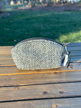 The Seashell Pouch in Black and White Herringbone Harris Tweed® has a curved top and flat base that stands up on its own, lined with natural heavy canvas.