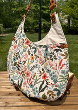 Close up of the Compass Rose Shoulder bag showing the Rifle Paper Co. Herb Garden Natural Canvas with Cognac Leather.