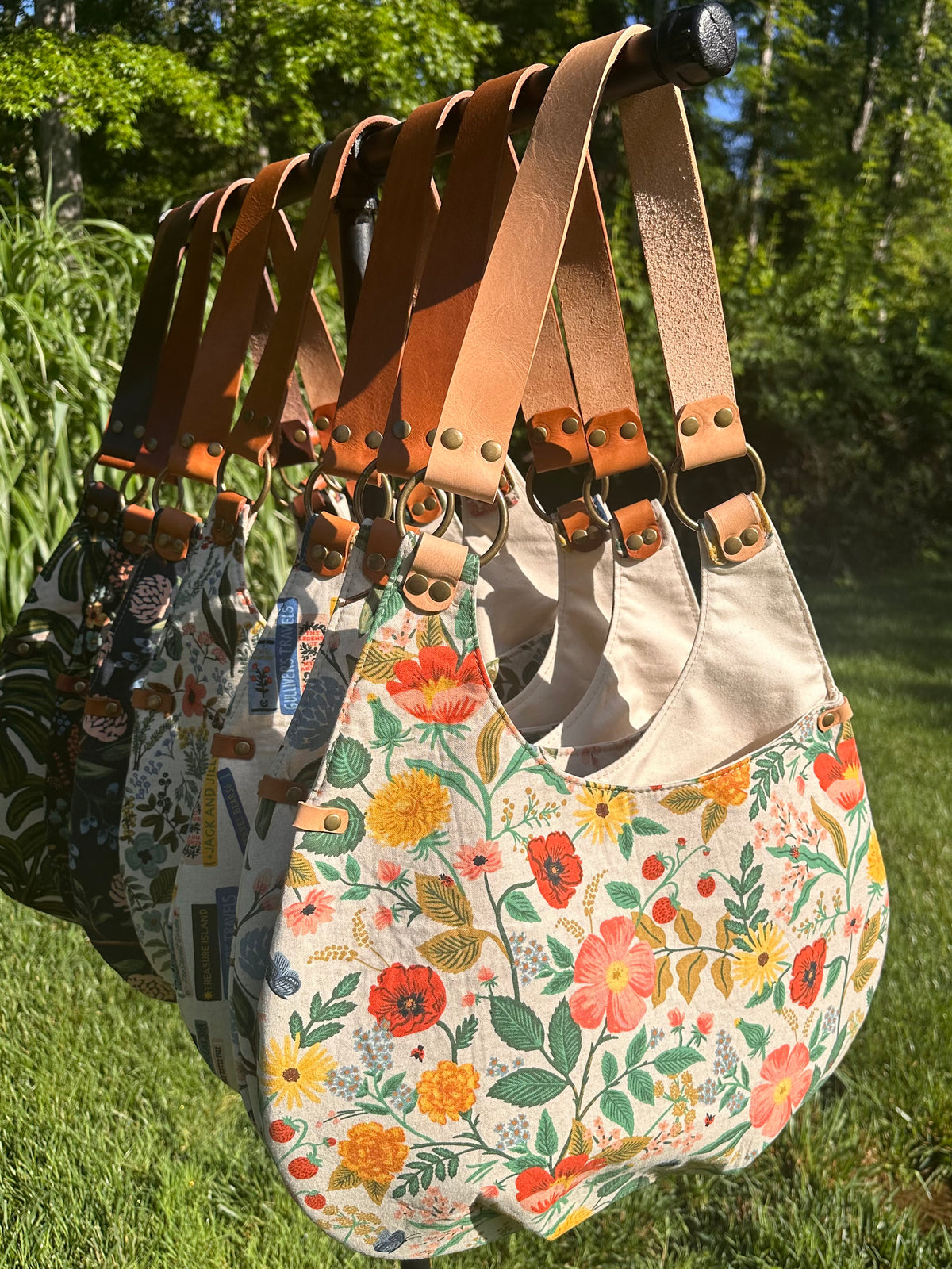 Large group of Compass Rose Shoulder Bag showing a variety of canvas design patterns and available leather straps.