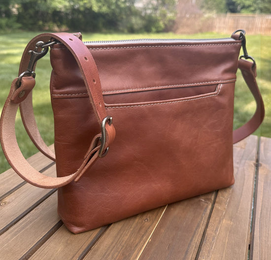 Front view of a handcrafted Leather Bayside Crossbody bag in Sienna Horween leather, showcasing its rich, warm color, natural grain, solid brass hardware, and full metal zipper. Designed and made in Maryland.