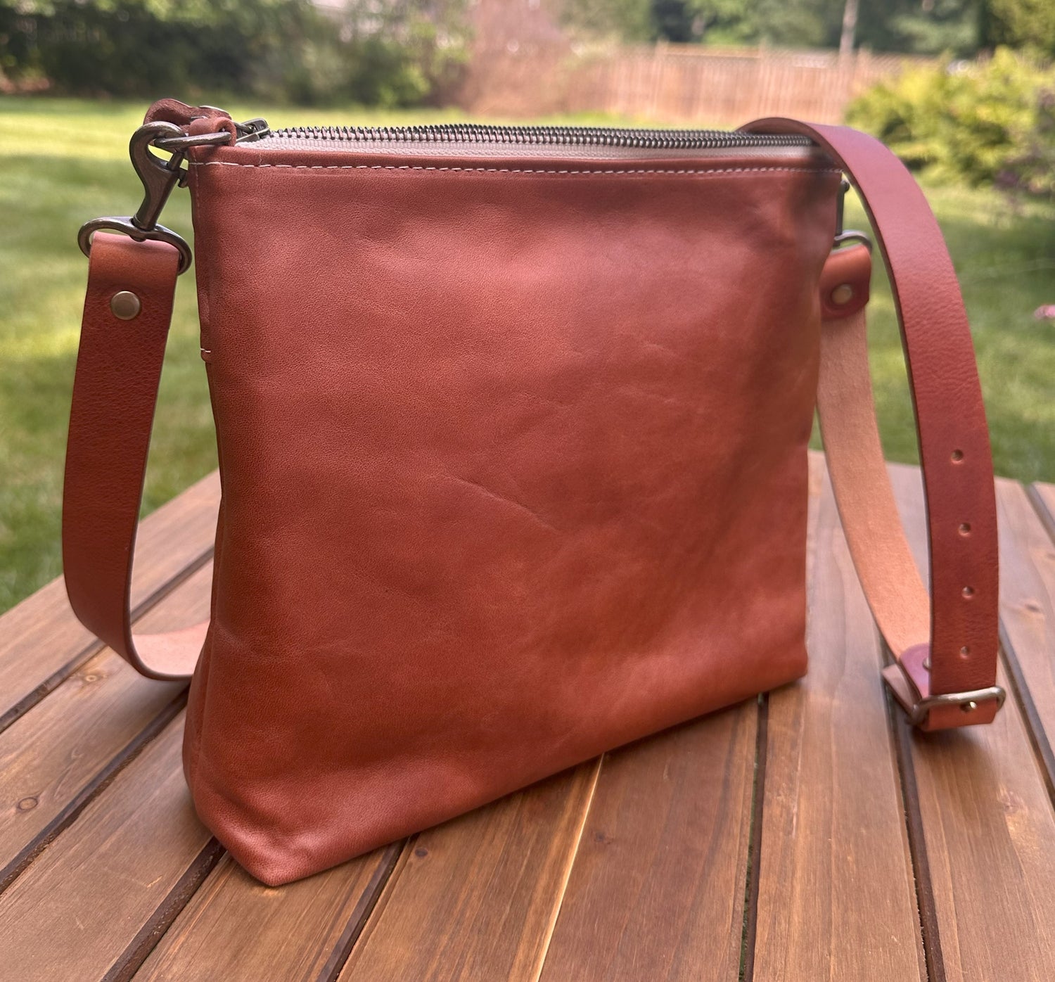 Back view of a handcrafted Leather Bayside Crossbody bag in Sienna Horween leather, showcasing its rich, warm color, natural grain, solid brass hardware, and full metal zipper. Designed and made in Maryland.