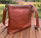 Back view of a handcrafted Leather Bayside Crossbody bag in Sienna Horween leather, showcasing its rich, warm color, natural grain, solid brass hardware, and full metal zipper. Designed and made in Maryland.