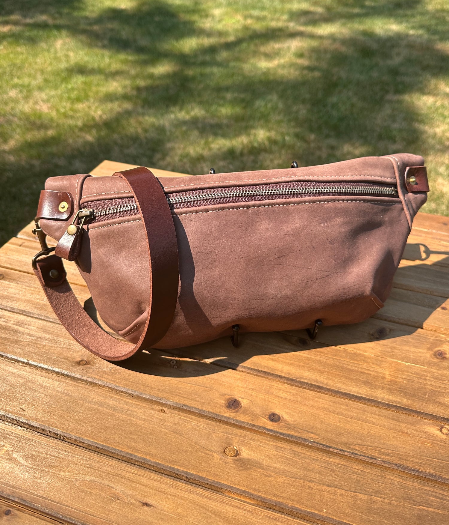 Front view of Leather Spinnaker Sling bag in Vintage Dark Brown leather with bronze hardware, linen interior, and front zipper. Unisex slim crossbody sling handmade in Maryland.