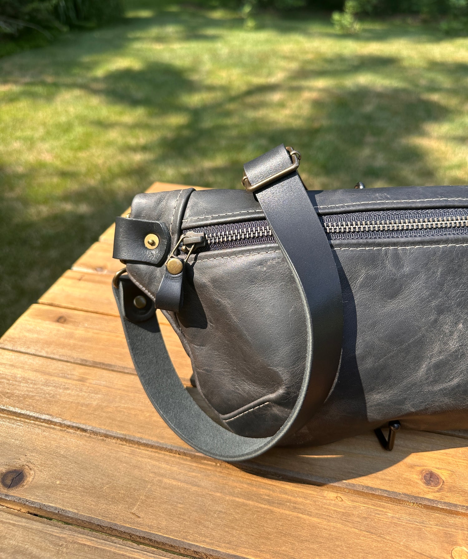 Close-up detail of the front zipper and grain texture on the Leather Spinnaker Sling in Rustic Charcoal Dublin Leather, with solid brass hardware and full-grain leather. Handcrafted in Maryland