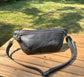 Front view of Leather Spinnaker Sling bag in Rustic Charcoal Dublin Leather with bronze hardware, linen interior, and front zipper. Unisex slim crossbody sling handmade in Maryland.