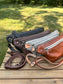 Collection of handcrafted leather Spinnaker Sling bags in rustic and smooth finishes, featuring full-grain leather, linen interior, and solid brass hardware. Handcrafted in Maryland