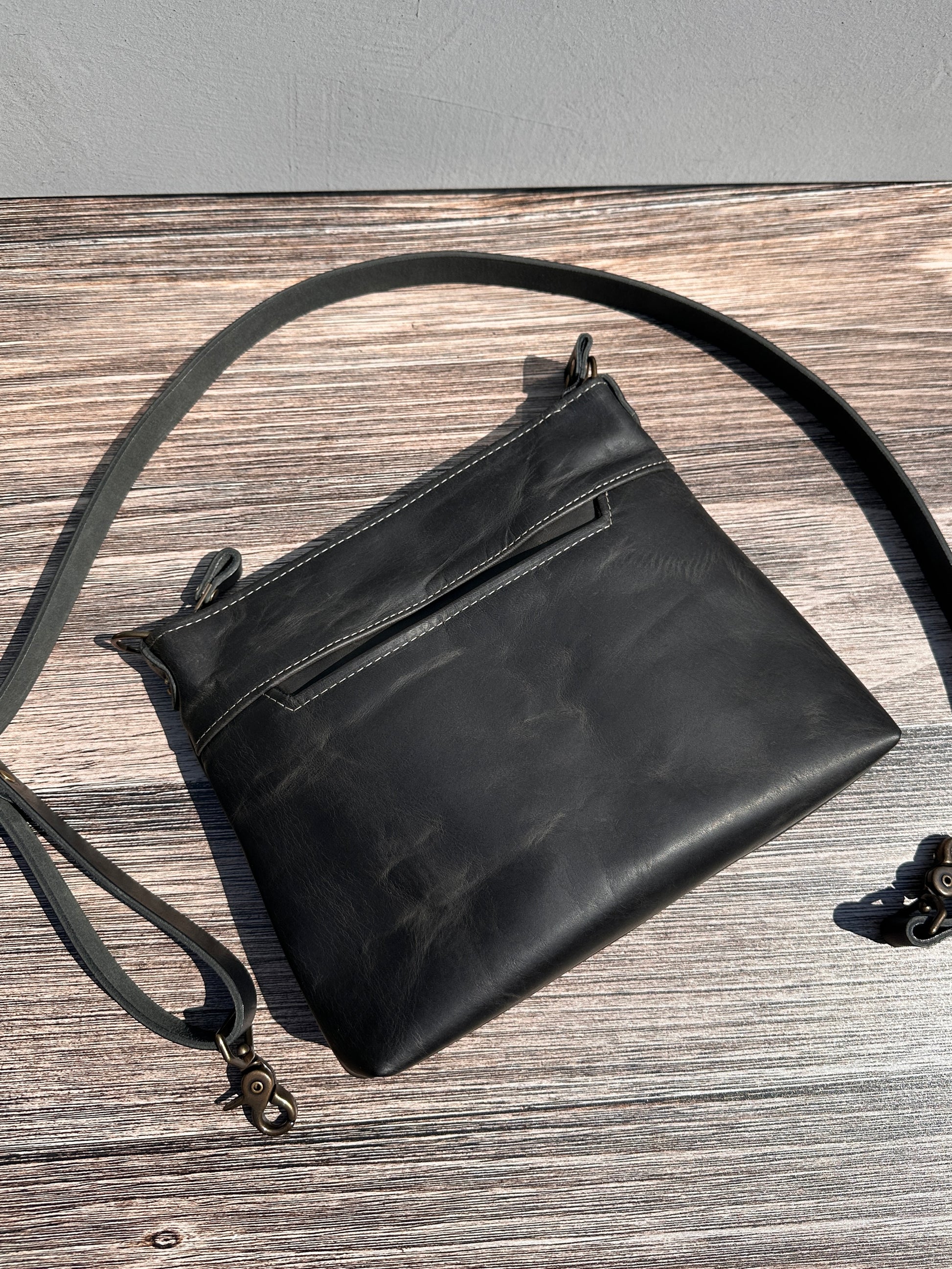 Rustic Charcoal Horween leather, showcasing its rich, warm color, natural grain, solid brass hardware, and full metal zipper. Designed and made in Maryland.