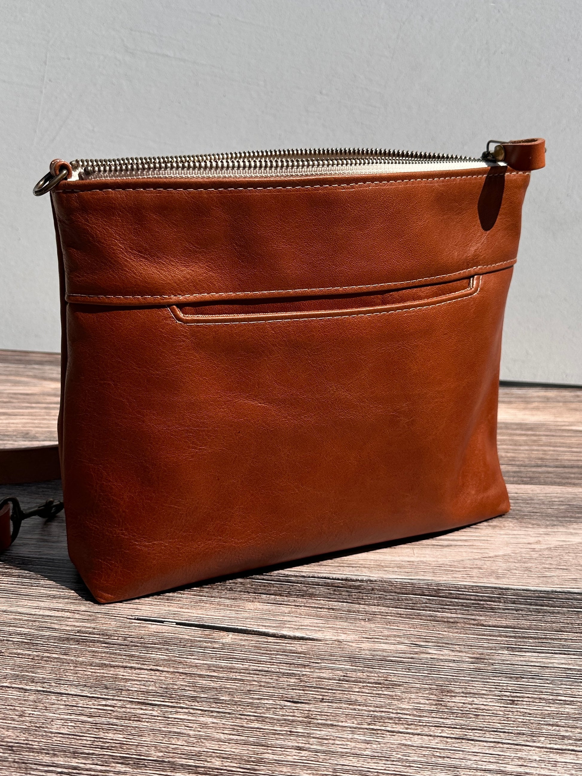 Front view of a handcrafted Leather Bayside Crossbody bag in Sienna Horween leather, showcasing its rich, warm color, natural grain, solid brass hardware, and full metal zipper. Designed and made in Maryland.