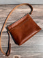 Overhead view of a handcrafted Leather Bayside Crossbody bag in Sienna Horween leather, showcasing its rich, warm color, natural grain, solid brass hardware, and full metal zipper. Designed and made in Maryland.