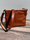 Back view of a handcrafted Leather Bayside Crossbody bag in Sienna Horween leather, showcasing its rich, warm color, natural grain, solid brass hardware, and full metal zipper. Designed and made in Maryland.