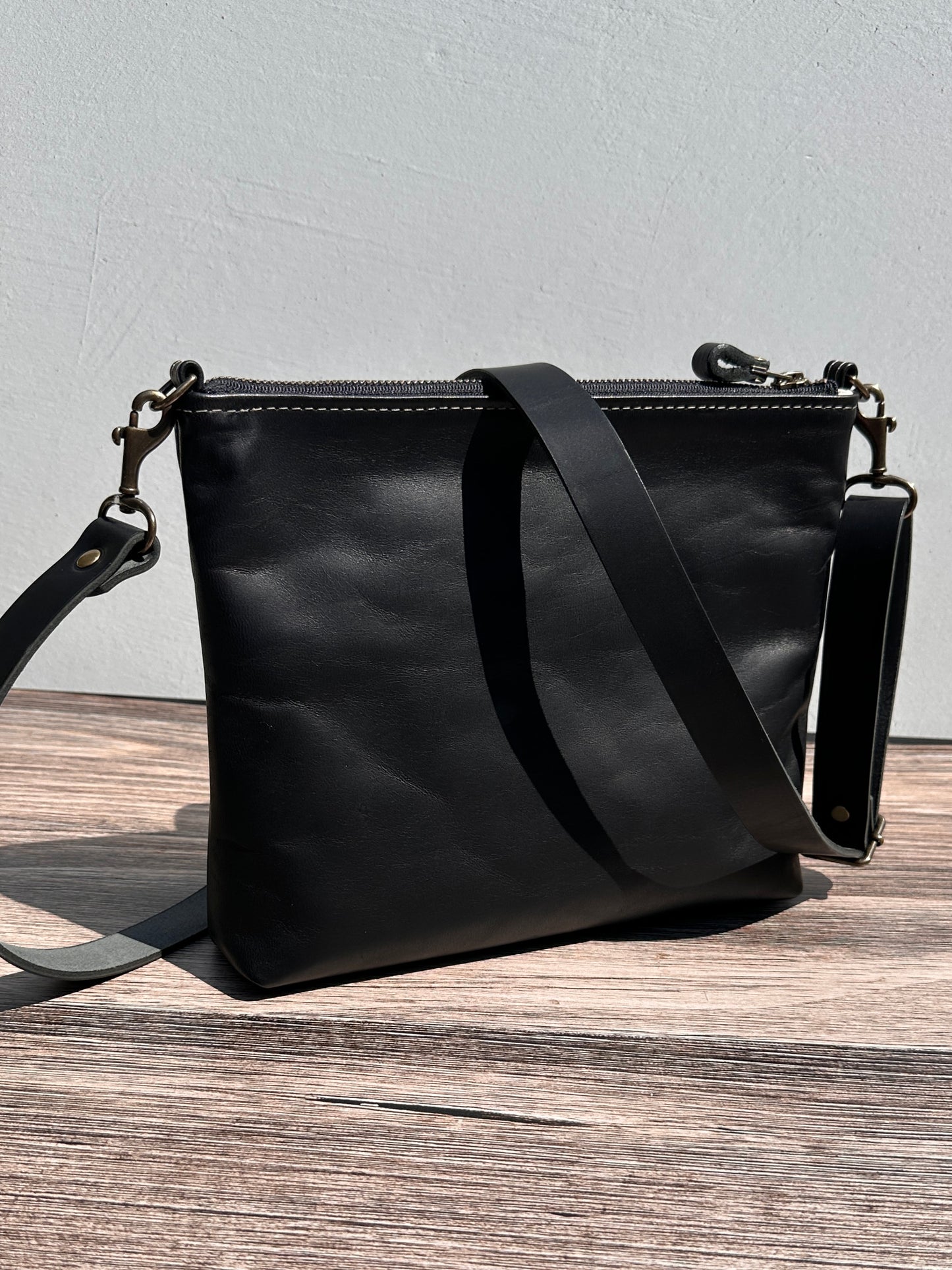 Back view of a handcrafted Leather Bayside Crossbody bag in Bomber Jacket Black Horween leather, showcasing its rich, warm color, natural grain, solid brass hardware, and full metal zipper. Designed and made in Maryland.