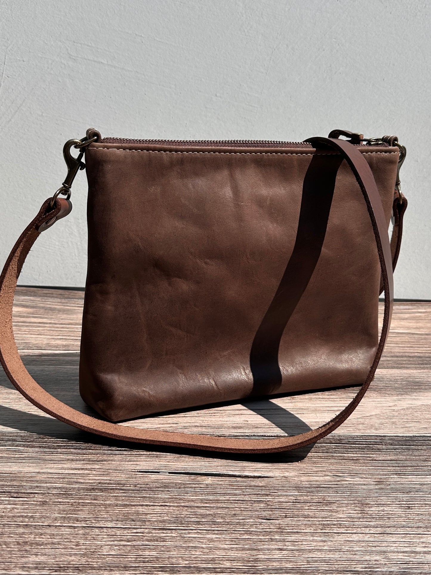 Back view of a handcrafted Leather Bayside Crossbody bag in Vintage Dark Brown Horween leather, showcasing its rich, warm color, natural grain, solid brass hardware, and full metal zipper. Designed and made in Maryland.