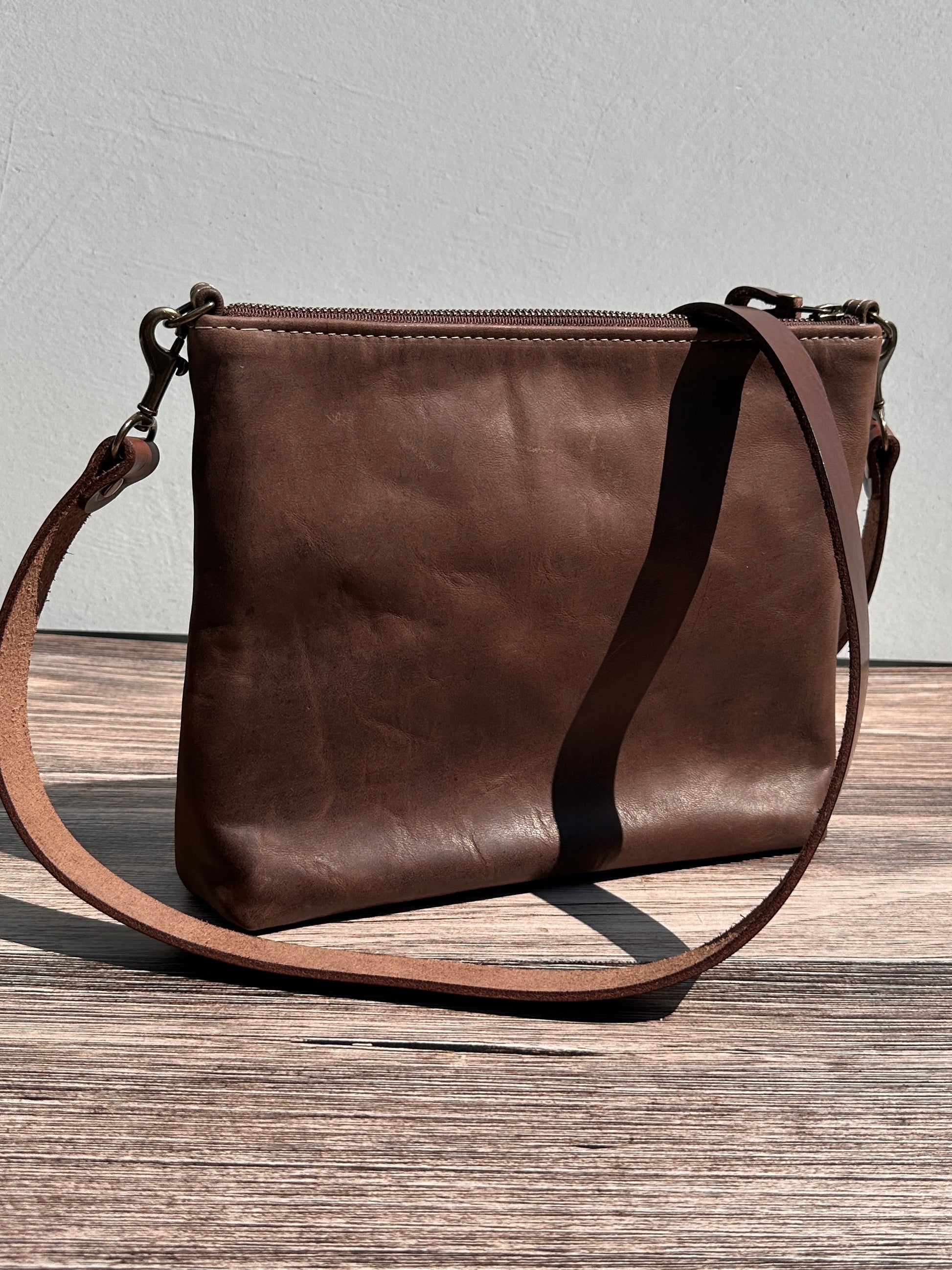 Back view of a handcrafted Leather Bayside Crossbody bag in Vintage Dark Brown Horween leather, showcasing its rich, warm color, natural grain, solid brass hardware, and full metal zipper. Designed and made in Maryland.