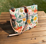 Front View Handcrafted Rifle Paper Co. Canvas Bayside Slim Crossbody Bag in Natural Botanical Floral Canvas with cotton canvas lining and adjustable Splenda vegetable-tanned leather strap.