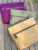 Collection of handcrafted Canvas Bayside Slim Crossbody Bags in waxed canvas, and solid canvas styles, with full canvas lining and adjustable vegetable-tanned leather straps.