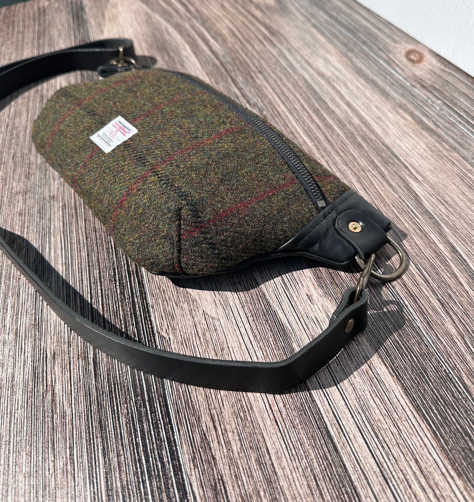 Minimalist sling bag handcrafted with Olive plaid Harris Tweed® and Horween Black Leather, finished with Antique Brass hardware.