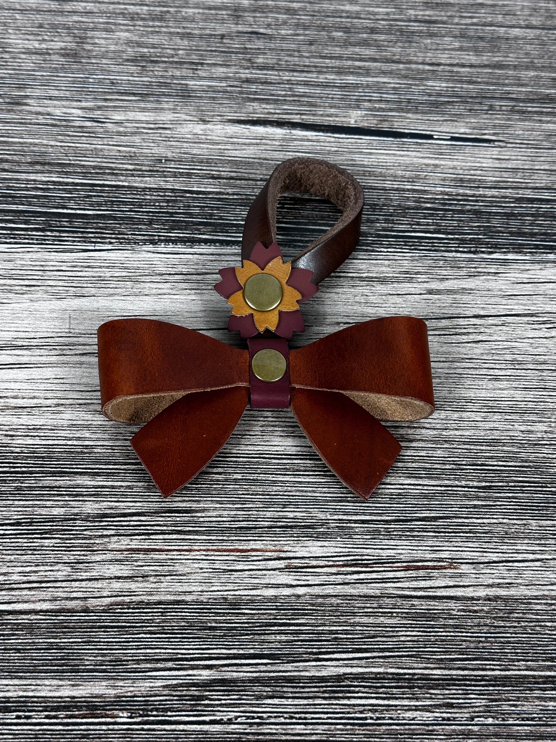Cognac Leather bow purse charm with snap closure styled on a leather shoulder bag.