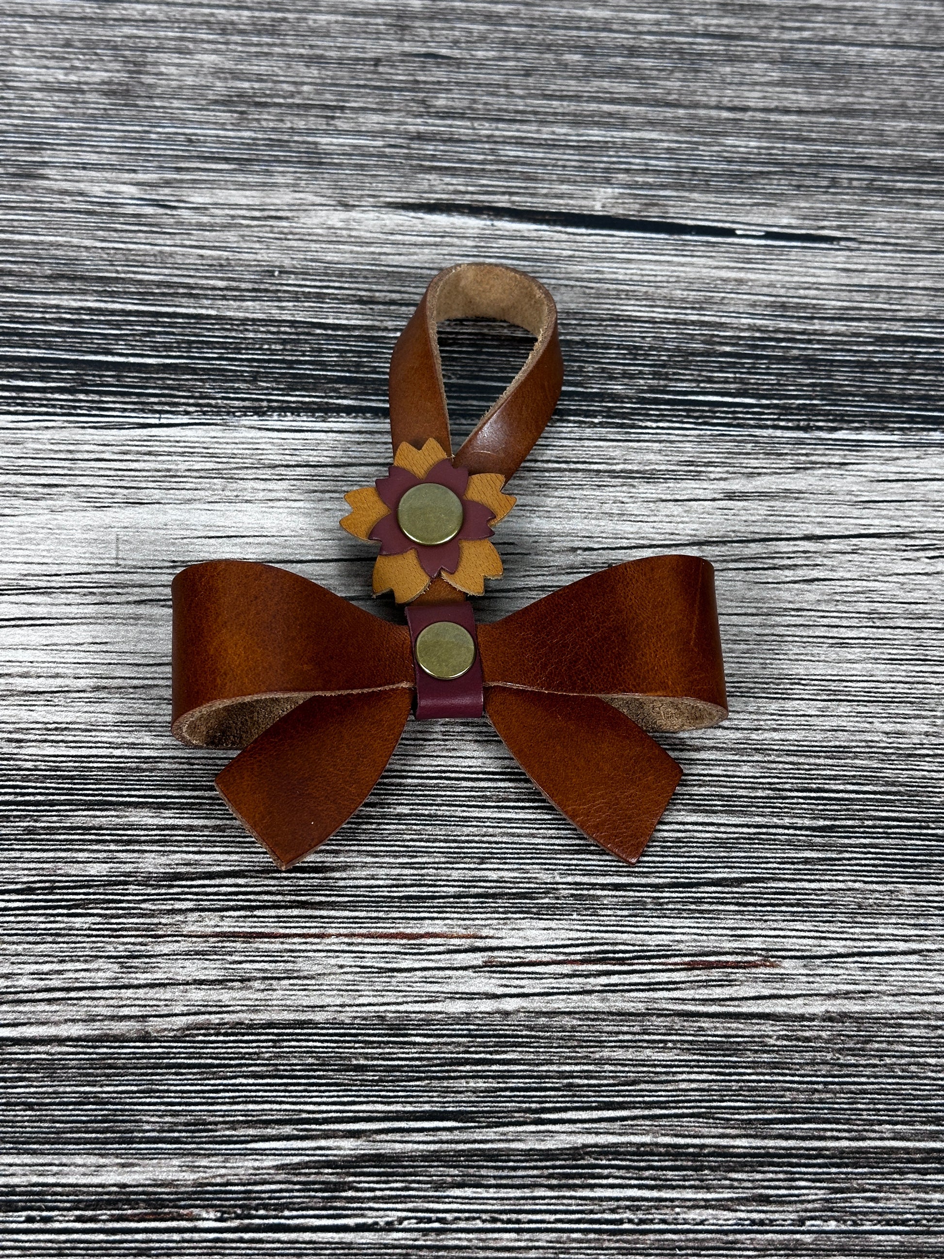 Cognac Leather bow purse charm with snap closure styled on a leather shoulder bag.