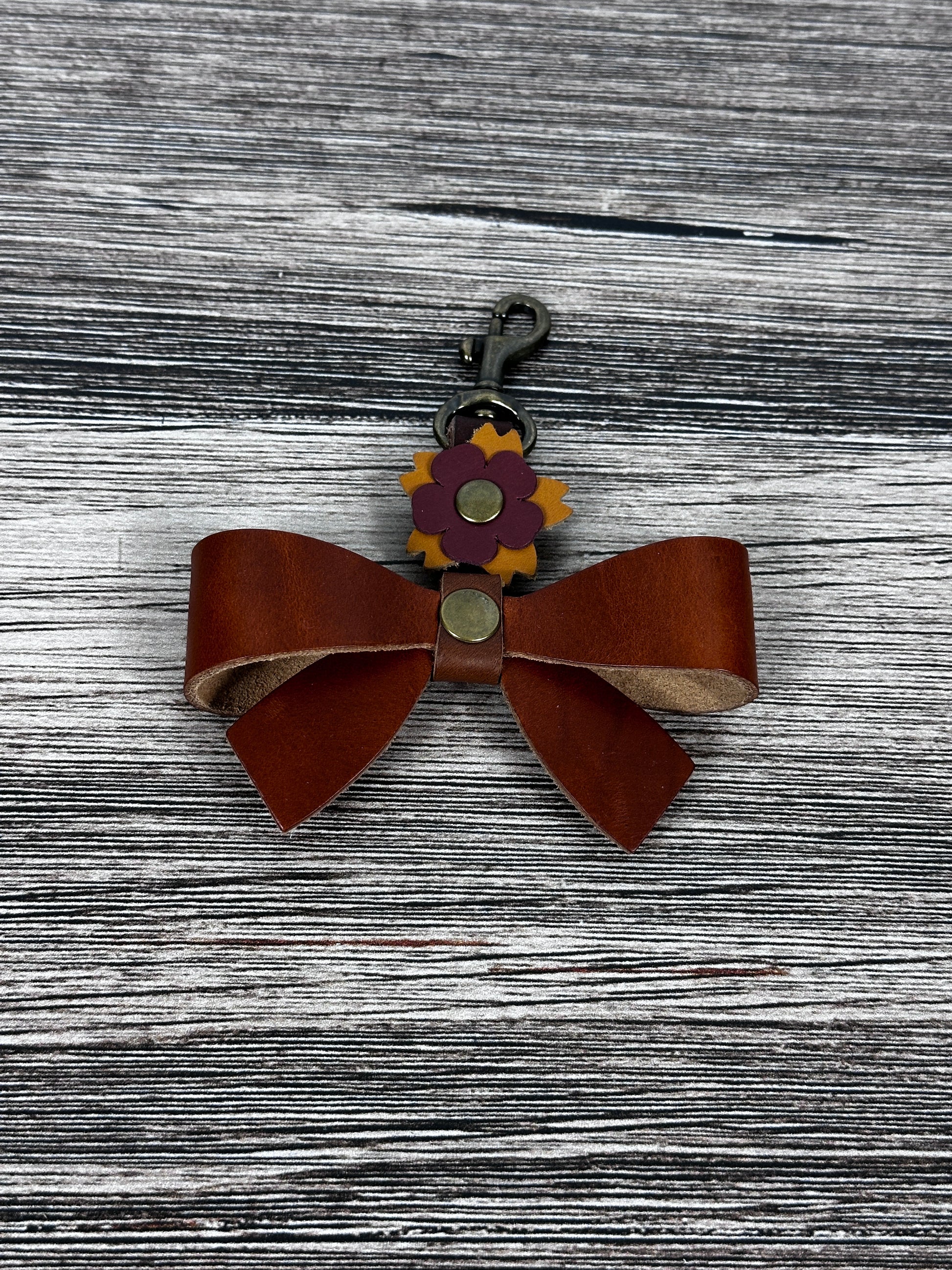 Leather bow handbag charm with swivel hook attached to tote handle.