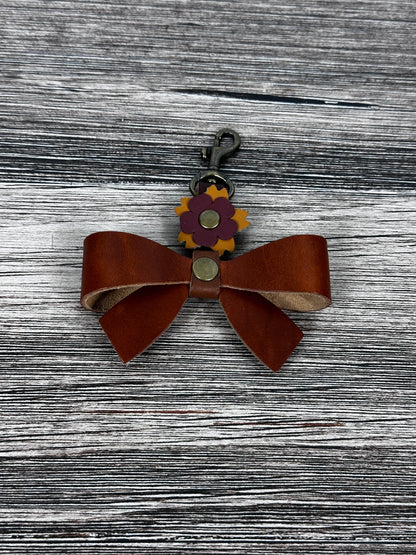 Leather bow handbag charm with swivel hook attached to tote handle.