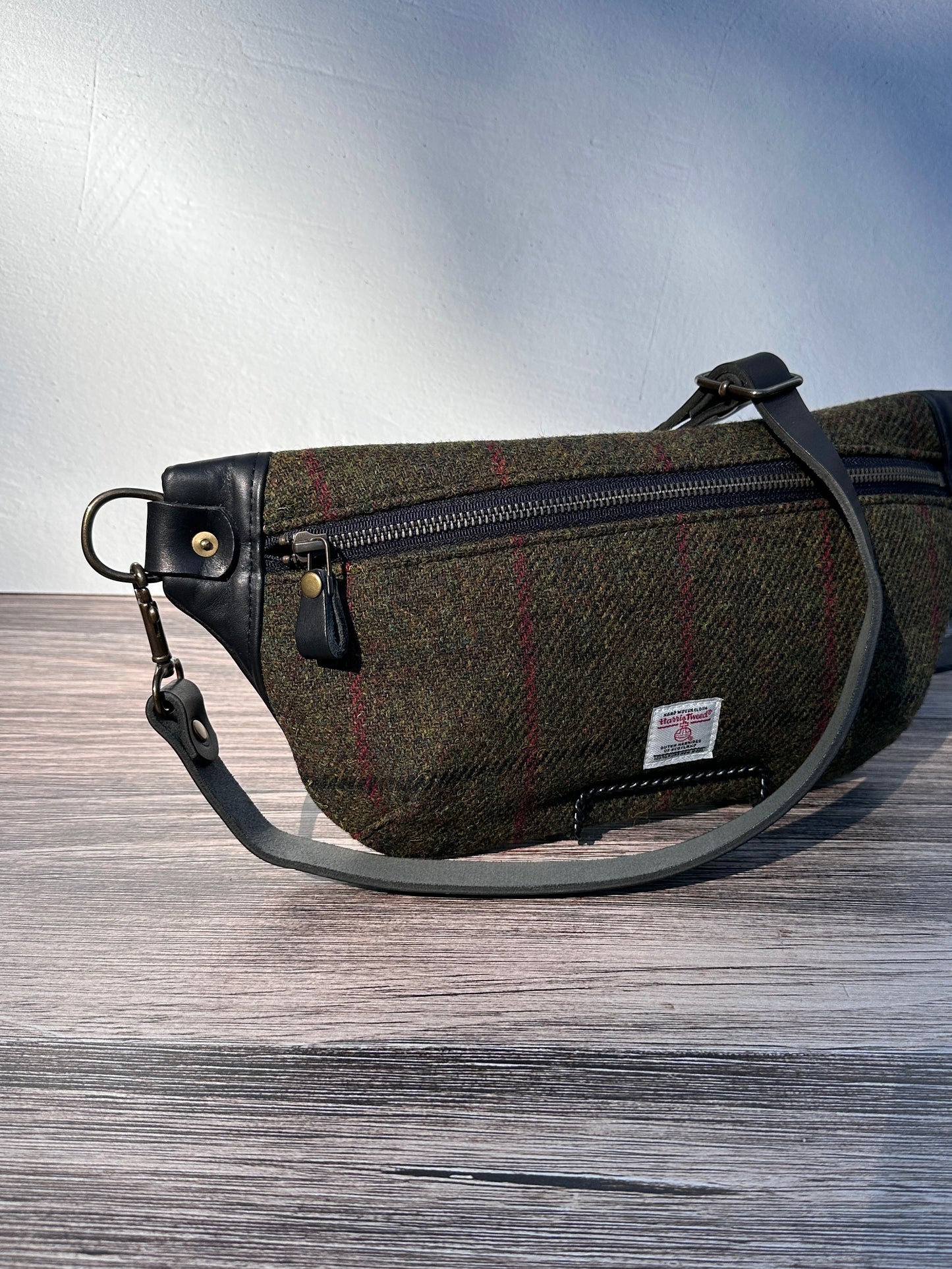 Minimalist sling bag handcrafted with Olive Plaid Harris Tweed® and Horween Black Leather, finished with Antique Brass hardware.
