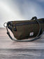 Minimalist sling bag handcrafted with Olive Plaid Harris Tweed® and Horween Black Leather, finished with Antique Brass hardware.