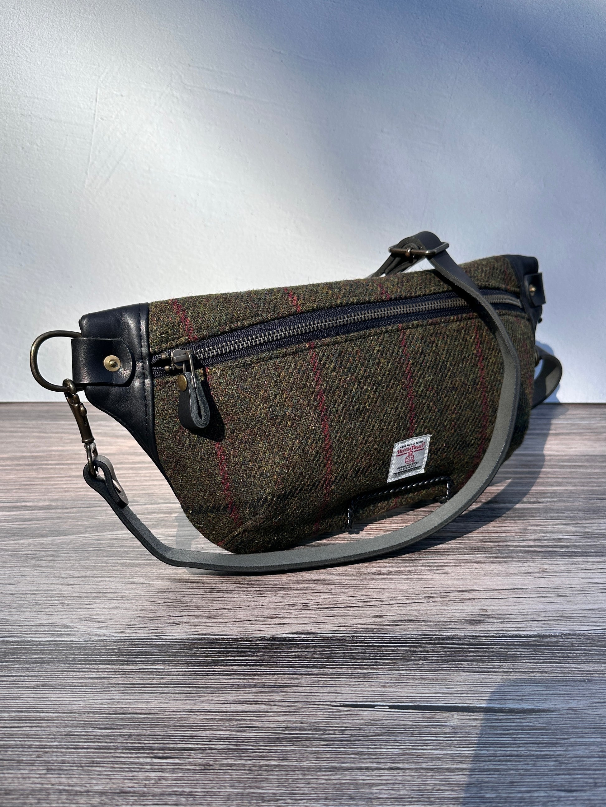 Minimalist sling bag handcrafted with Olive plaid Harris Tweed® and Horween Black Leather, finished with Antique Brass hardware.