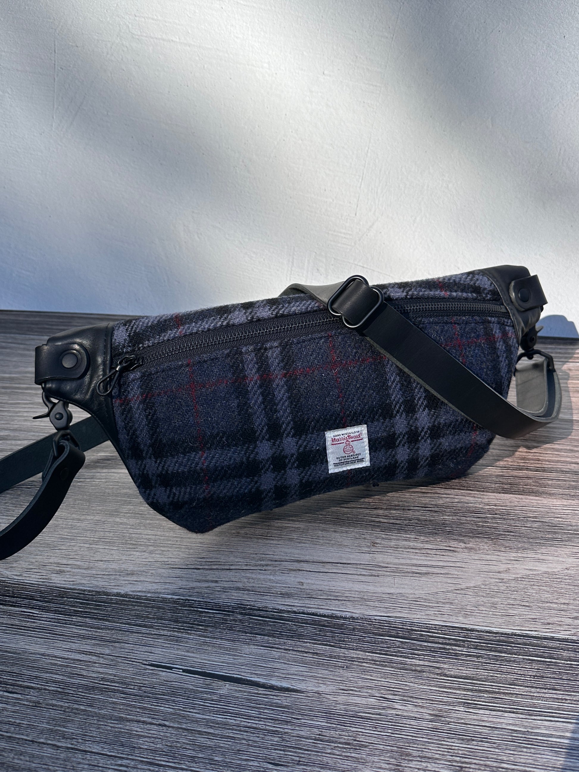 Minimalist sling bag handcrafted with Harris Tweed® and Horween Black Leather, finished with Matte Black hardware.