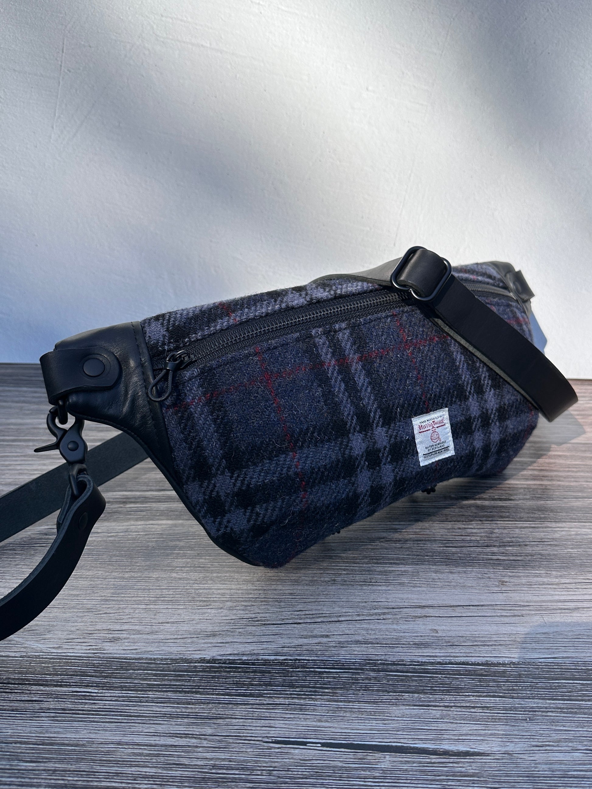 Minimalist sling bag handcrafted with Blue, Black and Grey plaid Harris Tweed® and Horween Black Leather, finished with Matte Black hardware.