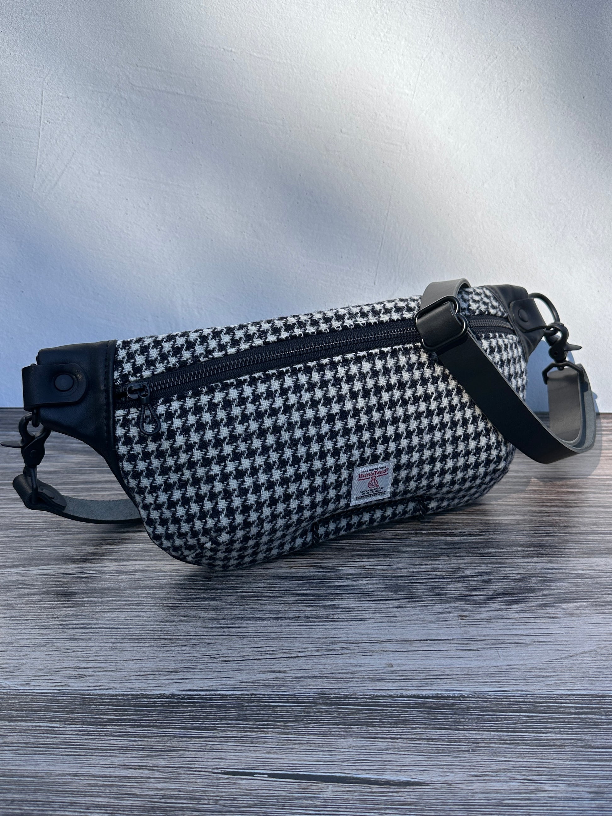 Minimalist sling bag handcrafted with Black and White Houndstooth Harris Tweed® and Horween Black Leather, finished with Matte Black hardware.