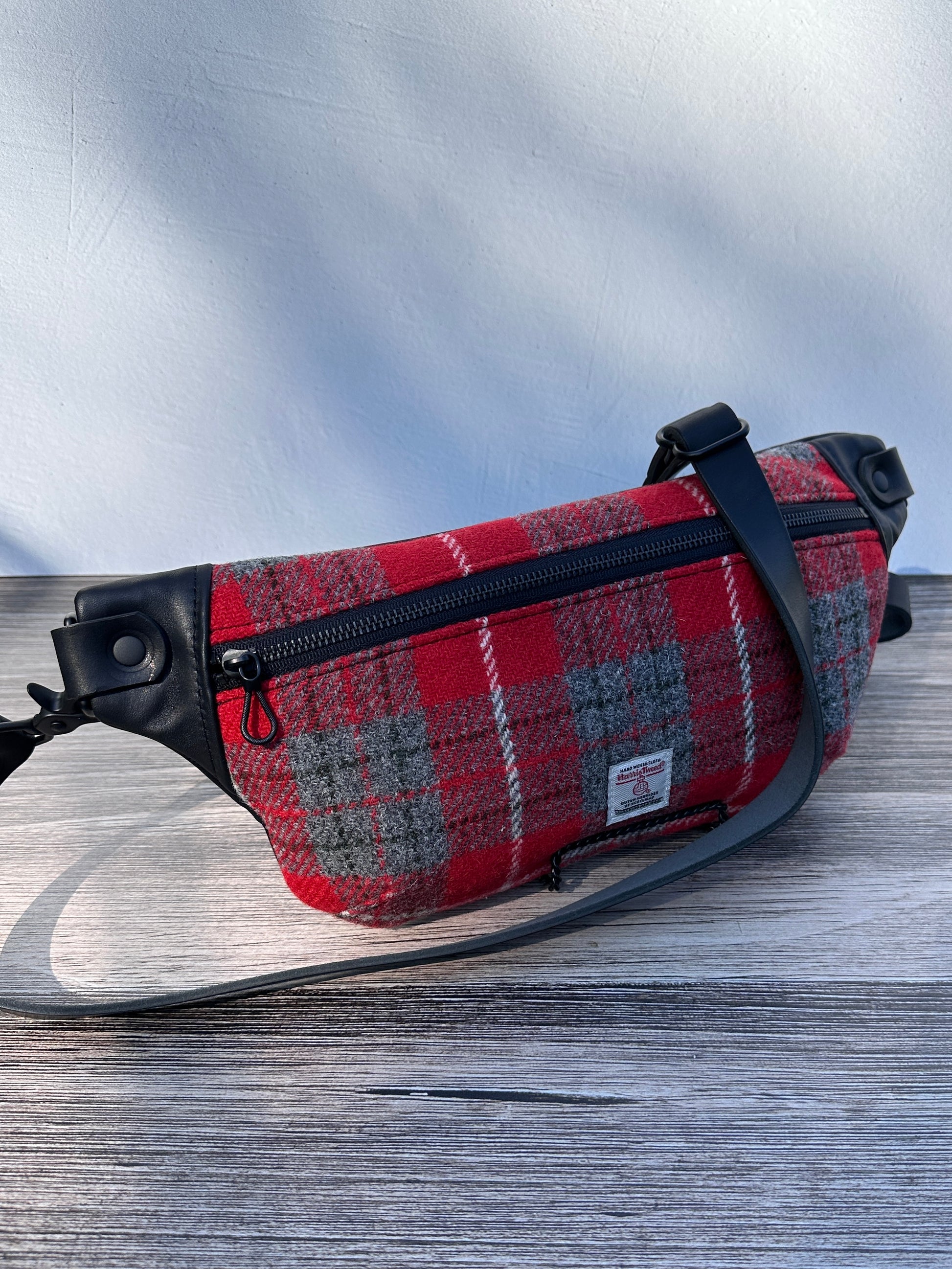 Minimalist sling bag handcrafted with Red and gray plaid Harris Tweed® and Horween Black Leather, finished with Matte Black hardware.