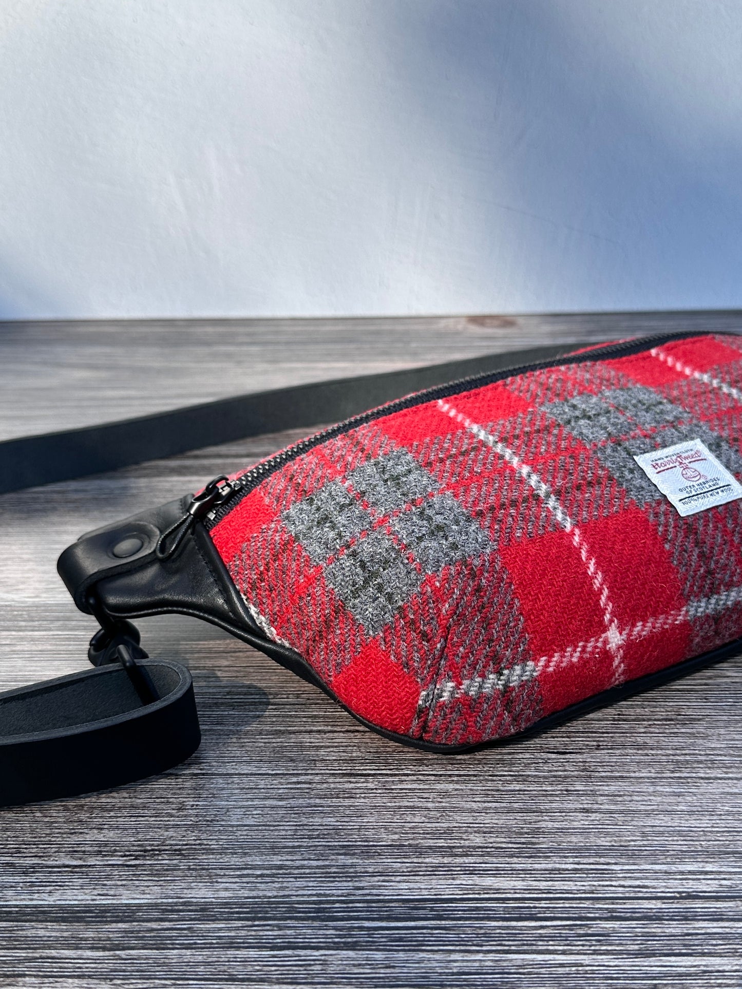 Minimalist sling bag handcrafted with Red and gray plaid Harris Tweed® and Horween Black Leather, finished with Matte Black hardware.