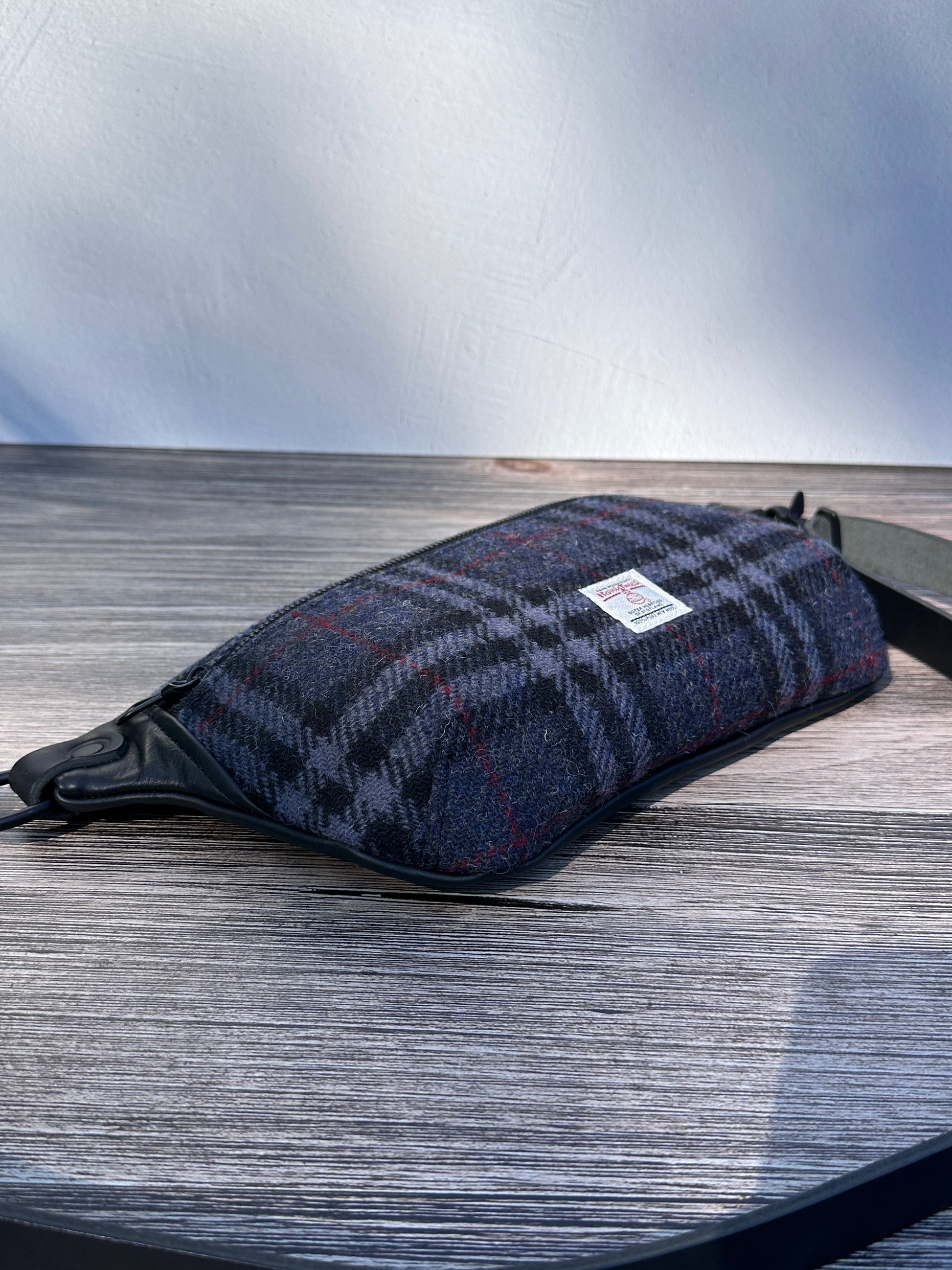 Minimalist sling bag handcrafted with Blue, Black and Grey plaid Harris Tweed® and Horween Black Leather, finished with Matte Black hardware.