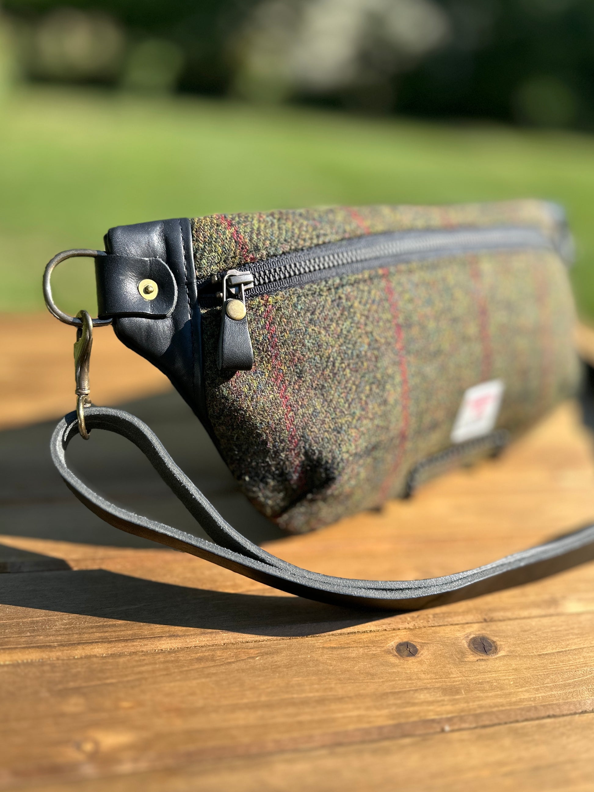 Minimalist sling bag handcrafted with Olive plaid Harris Tweed® and Horween Black Leather, finished with Antique Brass hardware.