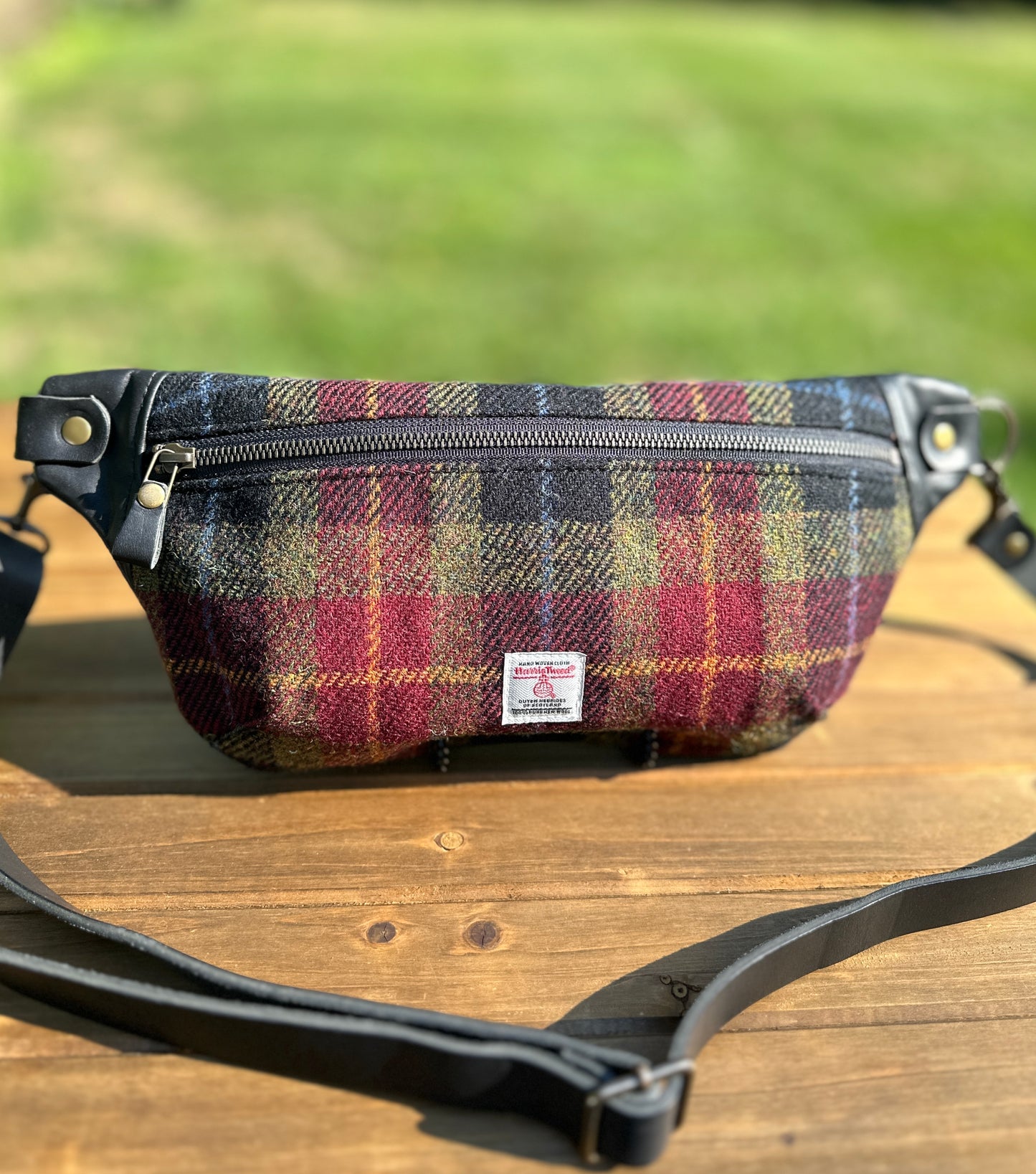Minimalist sling bag handcrafted with Green, Red and Black plaid Harris Tweed® and Horween Black Leather, finished with Antique Brass  hardware.