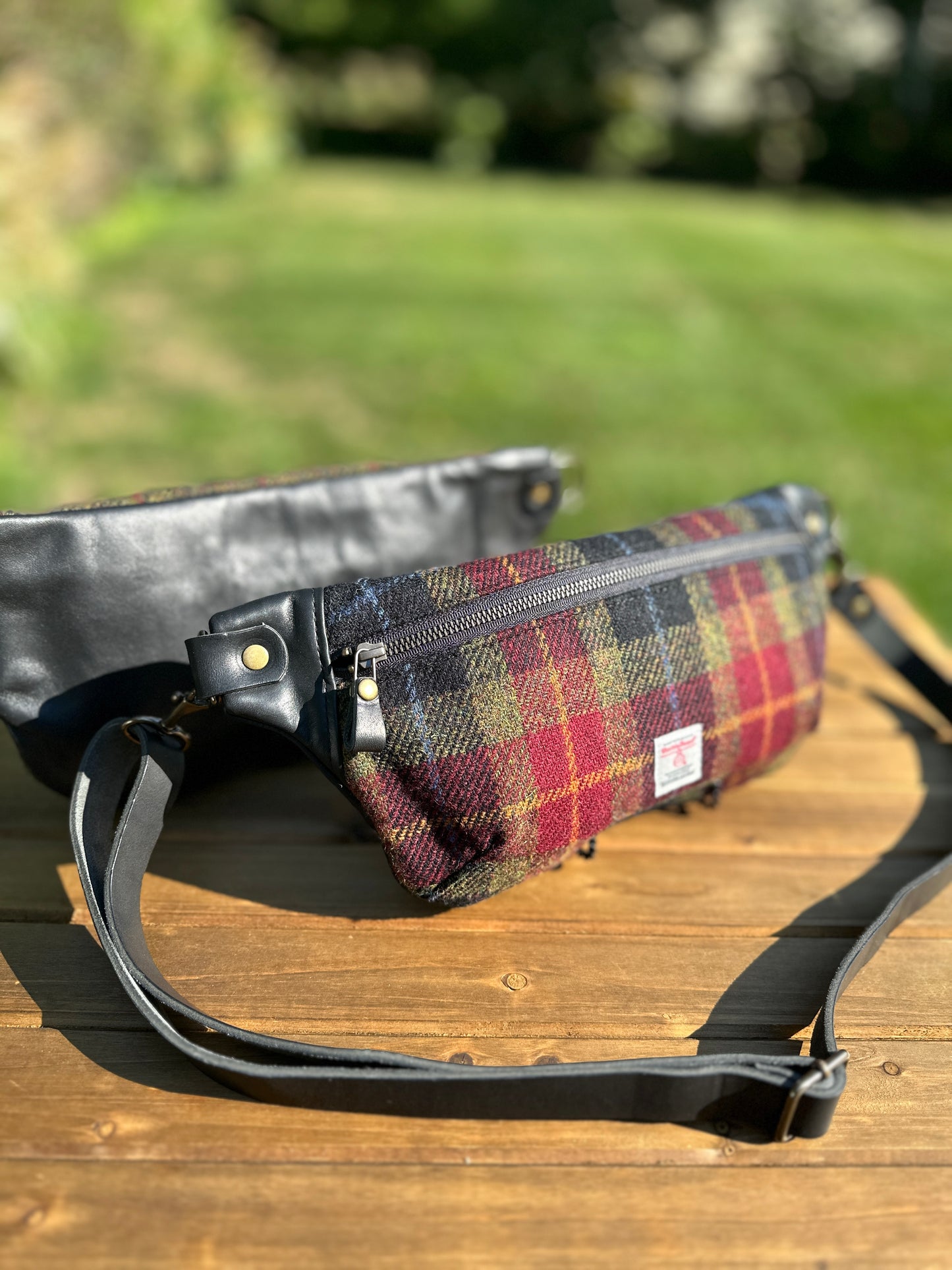 Minimalist sling bag handcrafted with Green, Red and Black plaid Harris Tweed® and Horween Black Leather, finished with Antique Brass  hardware.