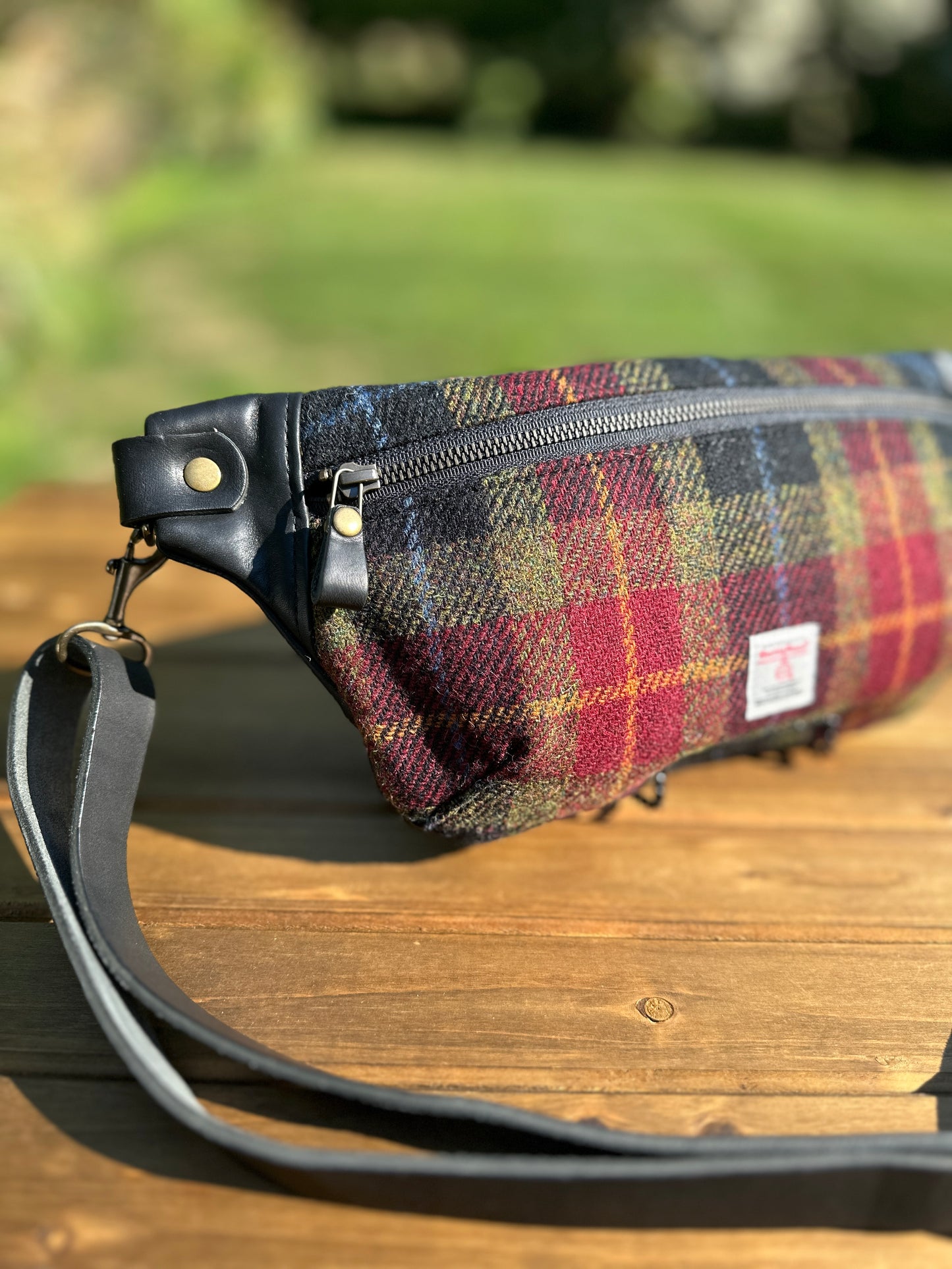 Minimalist sling bag handcrafted with Green, Red and Black plaid Harris Tweed® and Horween Black Leather, finished with Antique Brass  hardware.