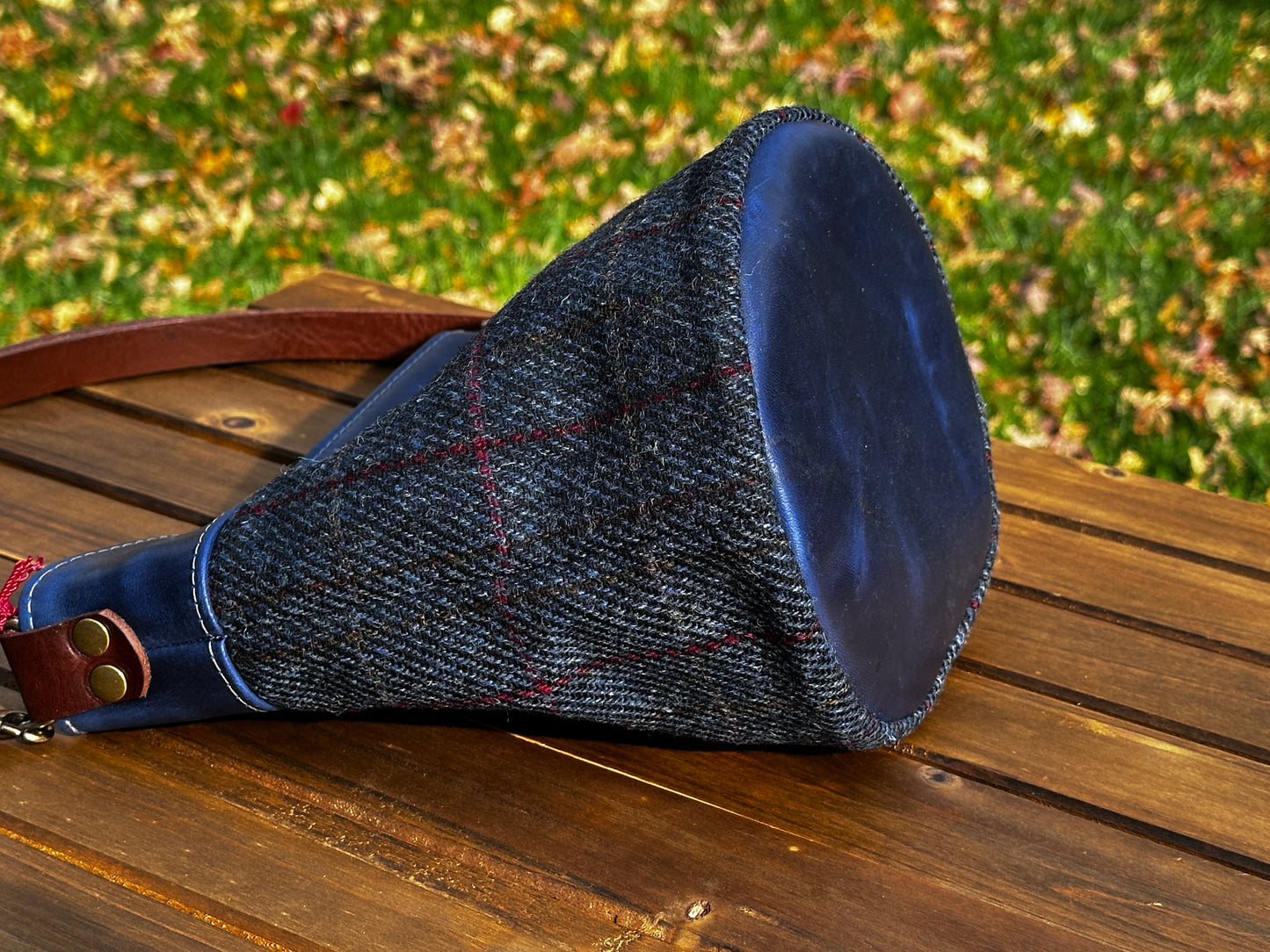 Harris Tweed® Lighthouse Crossbody round bag with flat bottom laying on side to show leather bottom