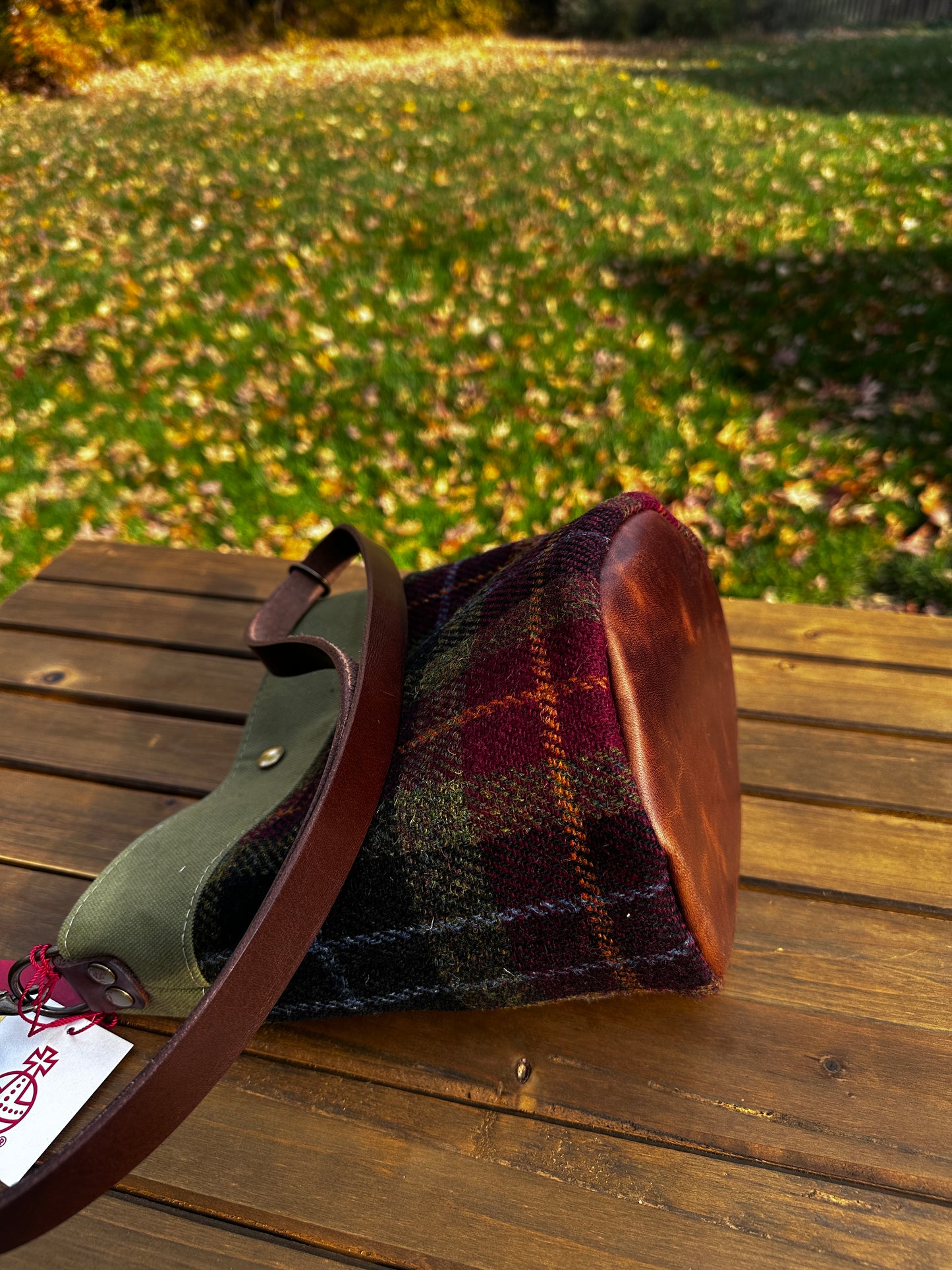 Harris Tweed® Lighthouse Crossbody round bag with flat bottom laying on side to show leather bottom