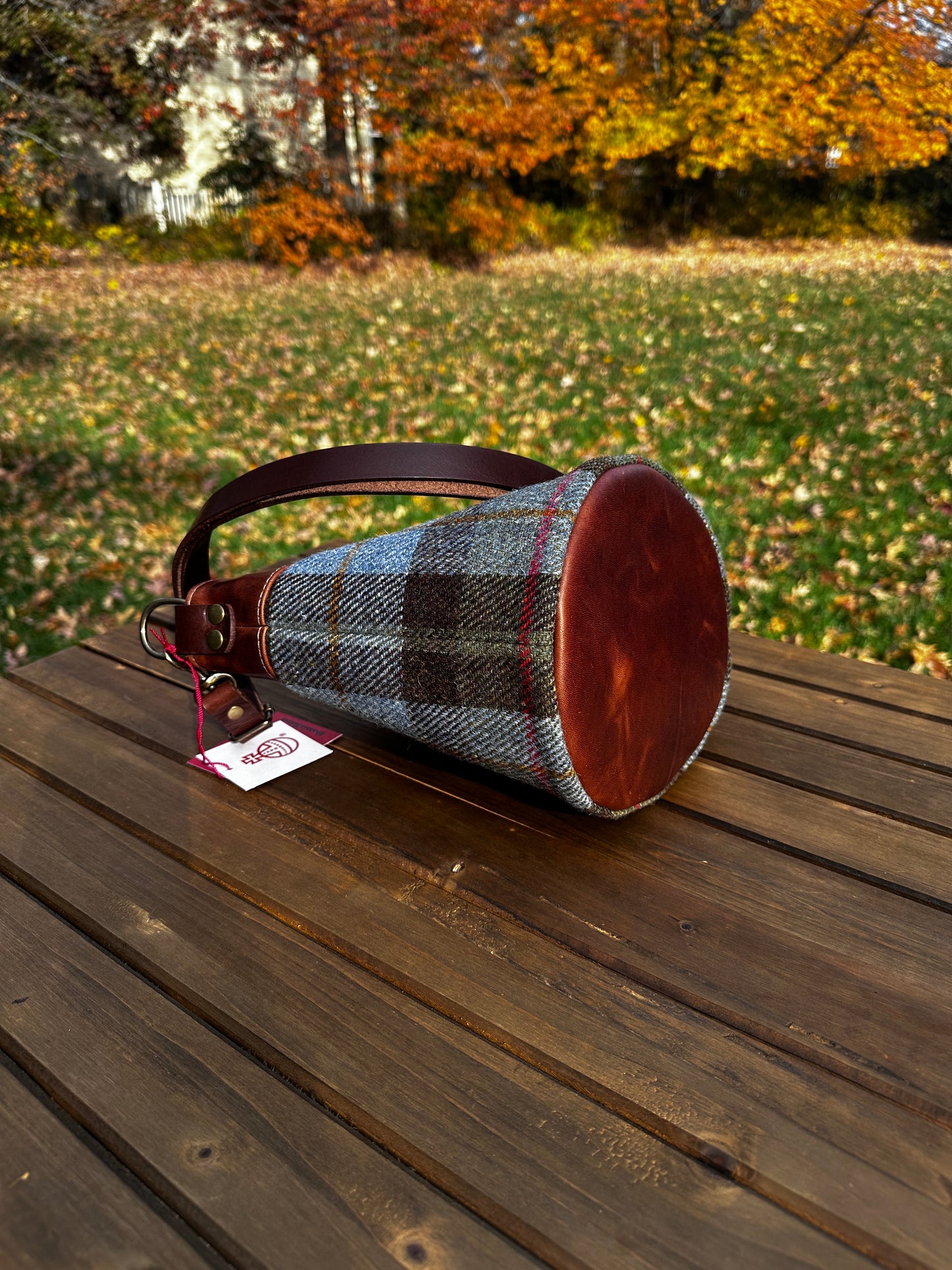 Harris Tweed® Lighthouse Crossbody round bag with flat bottom laying on side to show leather bottom