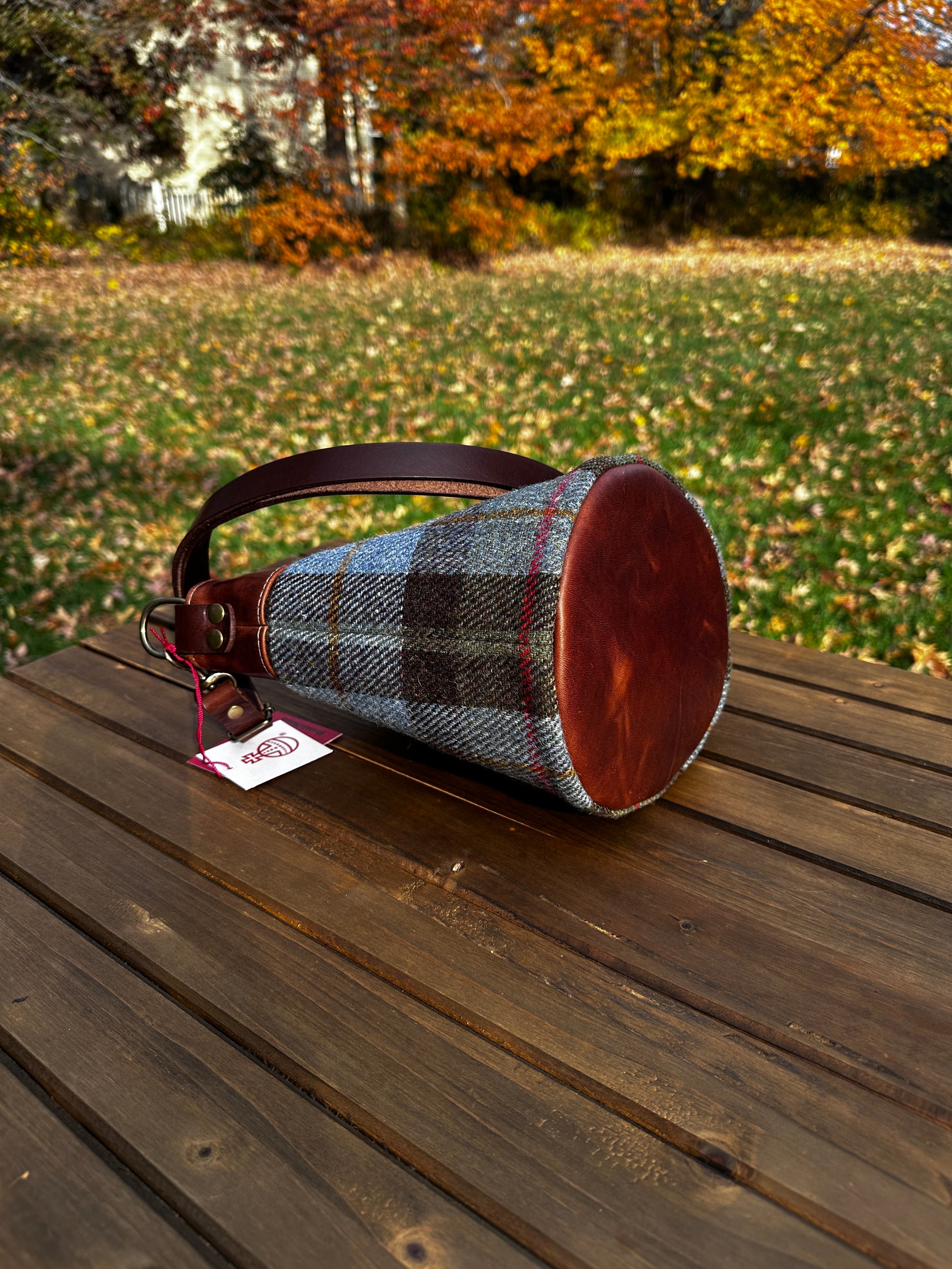 Harris Tweed® Lighthouse Crossbody round bag with flat bottom laying on side to show leather bottom