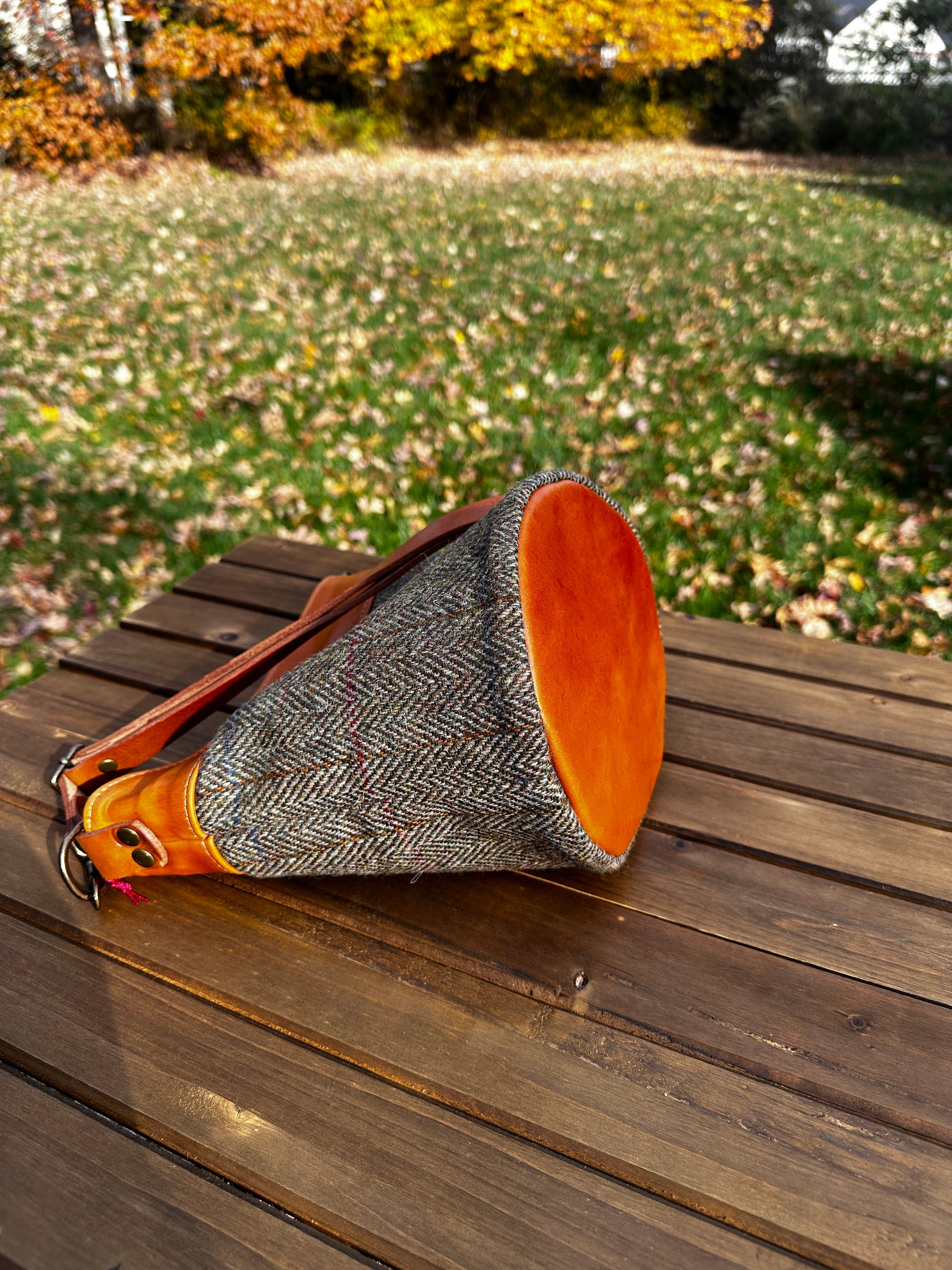 Harris Tweed® Lighthouse Crossbody round bag with flat bottom laying on side to show leather bottom