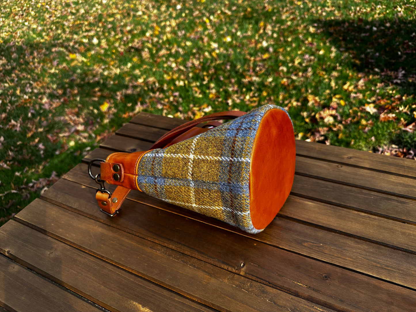 Harris Tweed® Lighthouse Crossbody round bag with flat bottom laying on side to show leather bottom