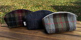 Three Seashell Pouch's in Red Green Black Plaid Harris Tweed®., Navy Window Pane Harris Tweed®. and Macleod Harris Tweed®.  The Seashell pouch has a curved top and flat base that stands up on its own and is lined with natural heavy canvas. 