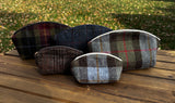 Three large Seashell Pouch's in Red Green Black Plaid Harris Tweed®., Navy Window Pane Harris Tweed®. and Macleod Harris Tweed® with two small Seashell Pouched in Warm Brown Harris Tweed® and Macleod Harris Tweed®. The Seashell pouch has a curved top and flat base that stands up on its own and is lined with natural heavy canvas. 