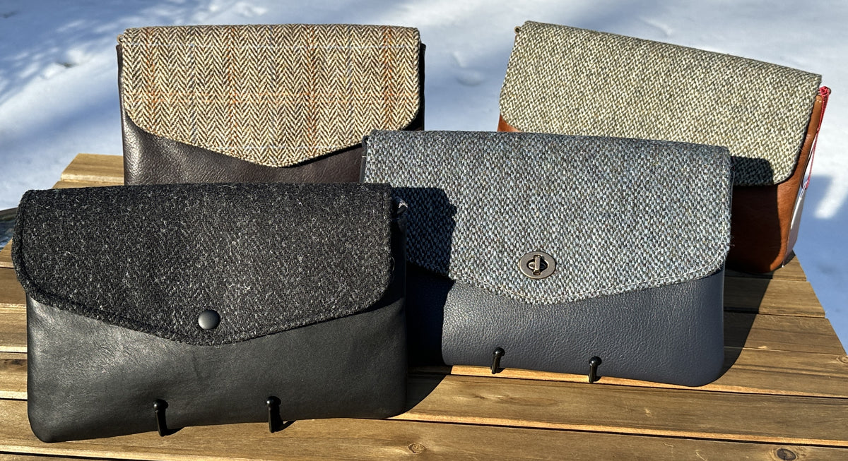 A collection of handcrafted Skye Fold clutches featuring authentic Harris Tweed flaps in grey, charcoal, and herringbone patterns. These elegant envelope clutches showcase a refined contrast between premium leather bodies and heritage Scottish wool.