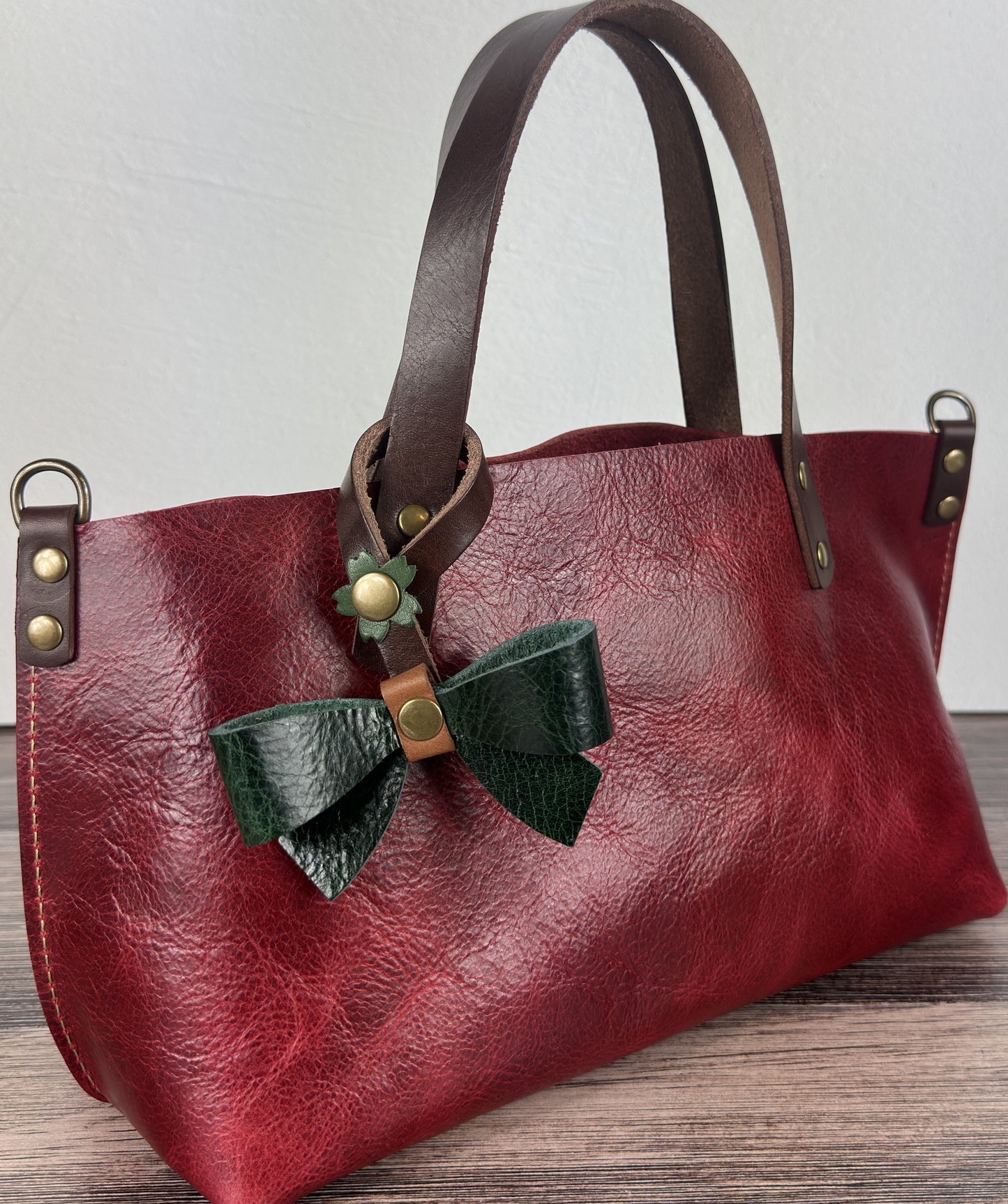 Leather bow bag charm clipped to a Leather Tote Handle – handcrafted purse accessory cut by hand.