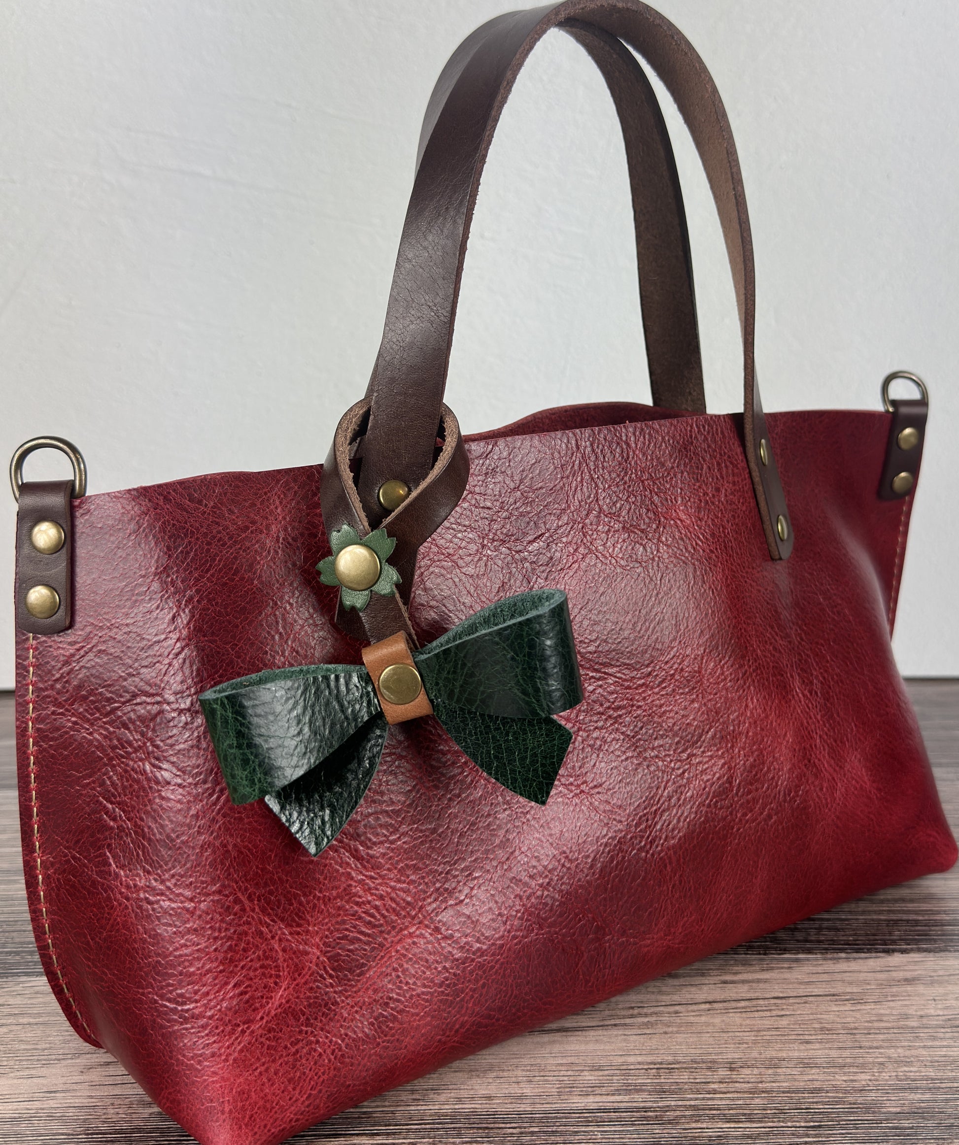 Leather bow bag charm clipped to a Leather Tote Handle – handcrafted purse accessory cut by hand.