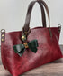 Leather bow bag charm clipped to a Leather Tote Handle – handcrafted purse accessory cut by hand.